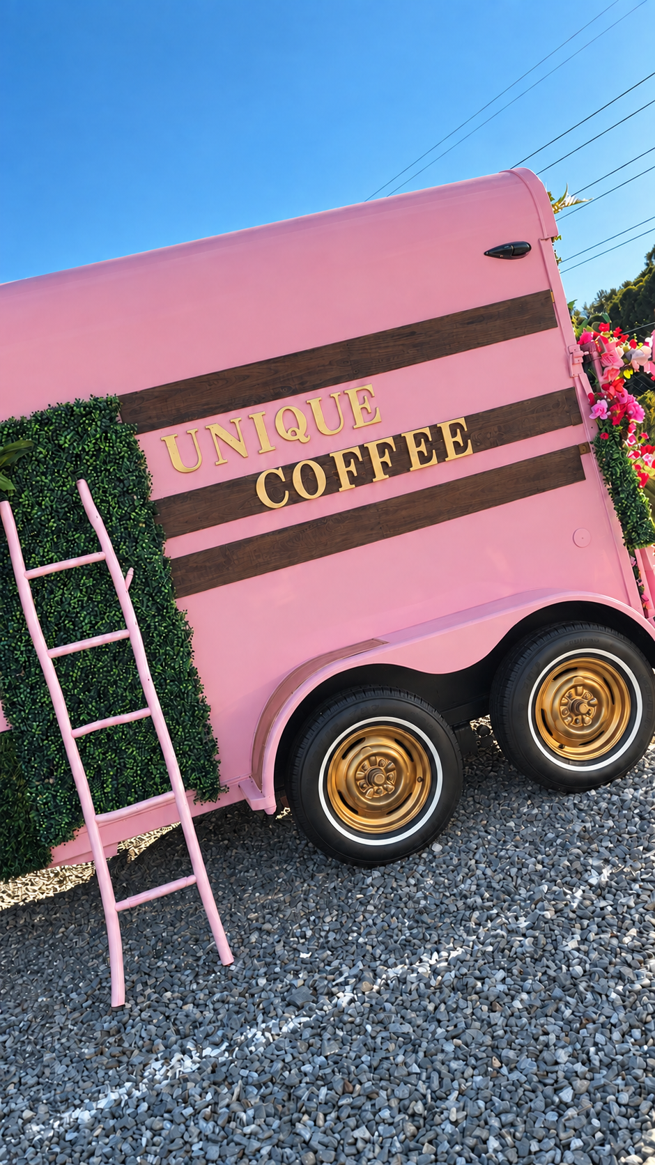 The actual pink Unique Coffee trailer with gold lettering and wheels